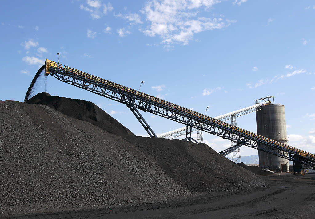 Conveyer belts rise over mounds of black coal.