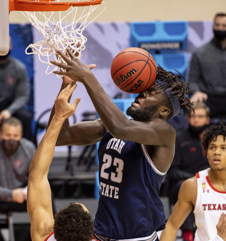 The basketball hits the face of Utah State center Neemias Queta (23) after his layup attempt ricocheted off the rim during the first half of a first round game against Texas Tech in the NCAA men's college basketball tournament, Friday, March 19, 2021, in Bloomington, Ind. (AP Photo/Doug McSchooler)