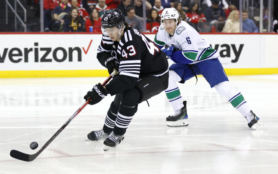 New Jersey Devils defenseman Luke Hughes (43) plays the puck against Vancouver Canucks right wing Brock Boeser (6) during the first period of an NHL hockey game, Saturday, Jan. 6, 2024, in Newark, N.J. (AP Photo/Noah K. Murray)