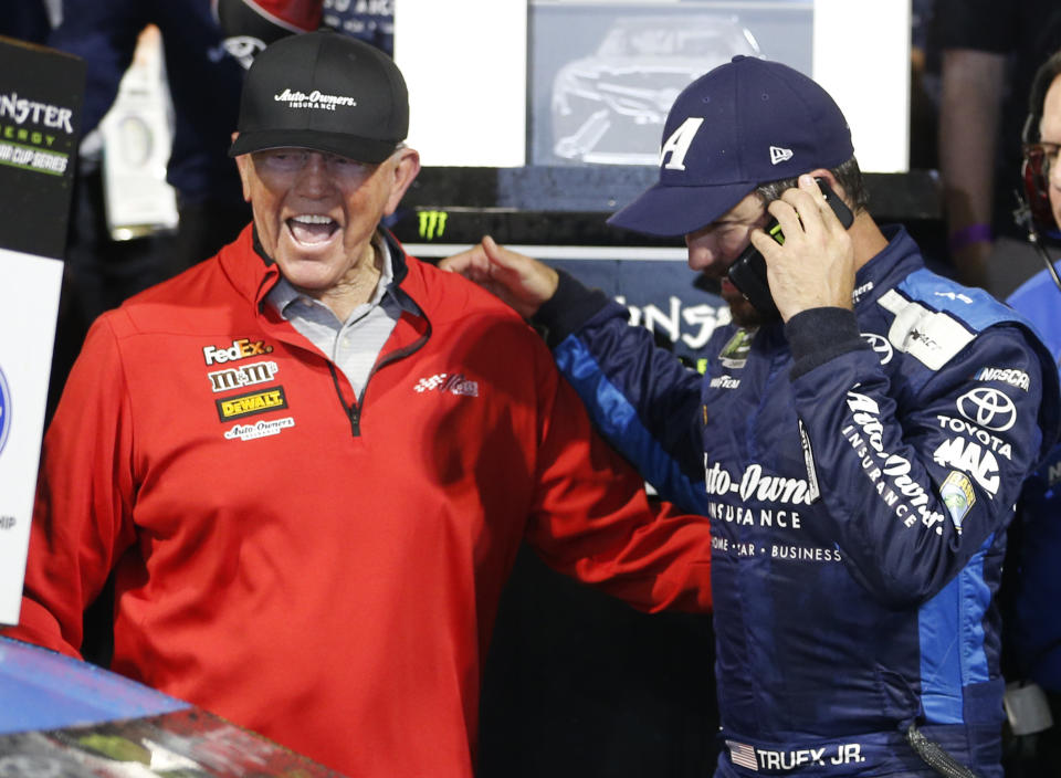 Martin Truex Jr. talks on a phone as he and team owner Joe Gibbs, left, celebrate winning the NASCAR Cup Series auto race at Richmond Raceway in Richmond, Va., Saturday, April 13, 2019. (AP Photo/Steve Helber)