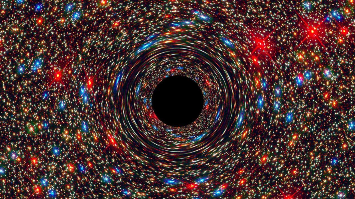  This computer-simulated image shows a supermassive black hole at the core of a galaxy. The black region in the center represents the black hole’s event horizon, where no light can escape the massive object’s gravitational grip. The black hole’s powerful gravity distorts space around it like a funhouse mirror. Light from background stars is stretched and smeared as the stars skim by the black hole. 