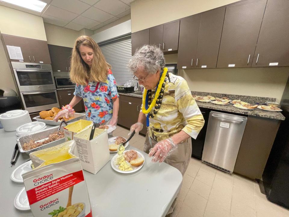 Sue Dolislager and Kitty Constantine serve up pulled BBQ pork and all the fixings at the luau at Karns Senior Center Tuesday, June 7, 2022.