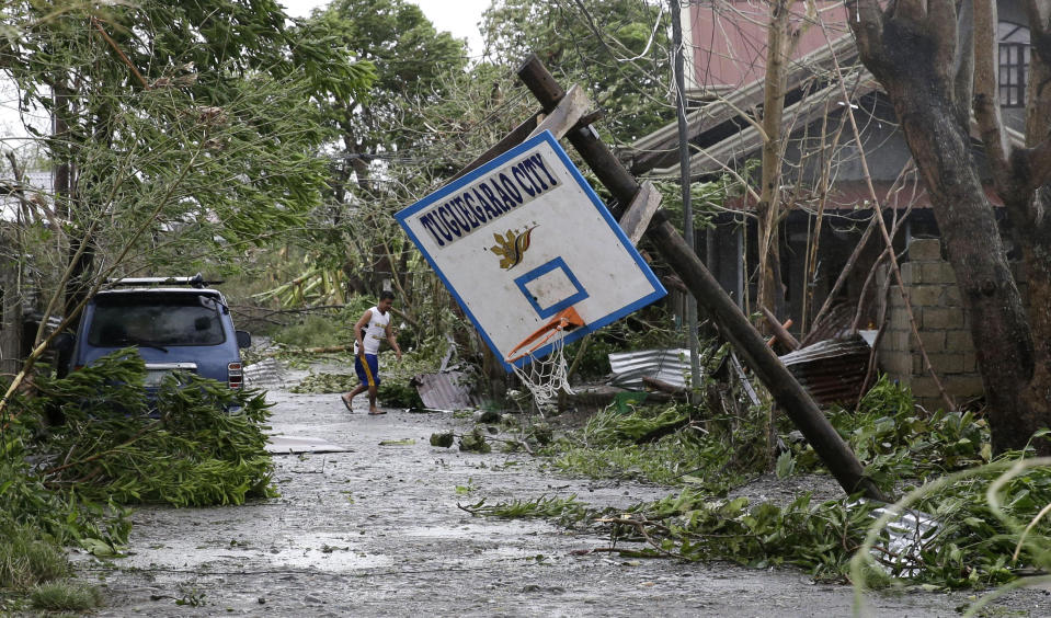 FILE - In this Saturday, Sept. 15, 2018, file photo, a resident walks beside a toppled basketball court after Typhoon Mangkhut barreled across Tuguegarao city, Cagayan province, northeastern Philippines. (AP Photo/Aaron Favila, File)