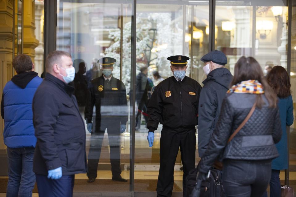 Security guards wearing face masks and gloves to protect from coronavirus, stand at an entrance of the GUM, State Department store after reopening in Moscow, Russia, on Monday, June 1, 2020. Monday's reopening of retail stores along with dry cleaners and repair shops comes as the pace of contagion has stabilized in the Russian capital that has accounted for about half of the nation's infections. (AP Photo/Alexander Zemlianichenko Jr)