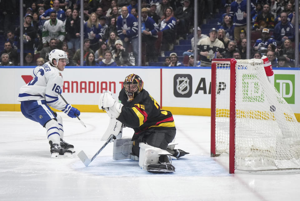 Toronto Maple Leafs' Mitchell Marner, left, scores a short-handed goal against Vancouver Canucks goalie Thatcher Demko, right, during the third period of an NHL hockey game in Vancouver, British Columbia, Saturday, Jan. 20, 2024. (Darryl Dyck/The Canadian Press via AP)