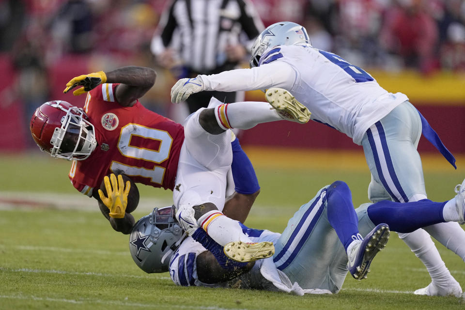 Kansas City Chiefs wide receiver Tyreek Hill (10) is stopped by Dallas Cowboys linebacker Keanu Neal, bottom, and safety Donovan Wilson (6) after catching a pass during the first half of an NFL football game Sunday, Nov. 21, 2021, in Kansas City, Mo. (AP Photo/Charlie Riedel)