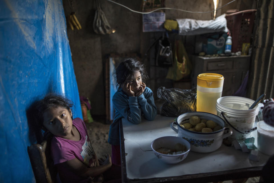 Fiorella Mendieta, de 11 años, a la izquierda, y su hermana Flavia, de 8 años, se sientan en la mesa de la cocina mientras esperan que les sirvan el almuerzo en su casa en el barrio Nueva Esperanza de Lima, Perú, el martes 2 de junio. 2020. (AP Foto/Rodrigo Abd)