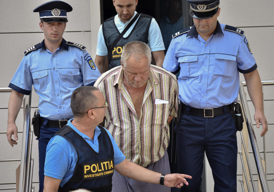 Police officers escort Gheorghe Dinca, the suspect in the case of rape and murder of a 15 year-old girl, from a court in Craiova, southern Romania, Saturday, July 27, 2019. Thousands of people took part Saturday evening in Bucharest in a march protesting the handling of the case, blaming Romanian officials for negligence, incompetence and a lack of empathy. (AP Photo/Bogdan Danescu)