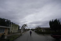 Ileana Miranda walks past an old San Jerardo cooperative water tank, at left, during an interview in Salinas, Calif., Wednesday, Dec. 20, 2023. Some California farming communities have been plagued for years by problems with their drinking water due to nitrates and other contaminants in the groundwater that feeds their wells. (AP Photo/Jeff Chiu)