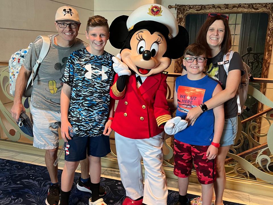 kari and her family posing with minnie mouse on the disney wish cruise ship