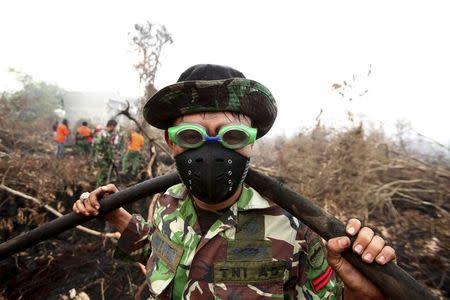 An Indonesian soldier uses swimming goggles to protect his eyes from smoke while helping to fight a fire in a peatland forest area in Parit Indah Village, Kampar, Riau province, Indonesia, September 8. 2015. REUTERS/YT Haryono