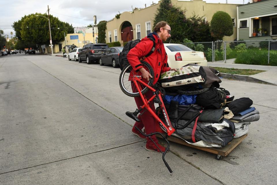 Charles McKnight moves his belongings along Logan St. before LAPD officers evict homeless from an encampment in Echo Park.