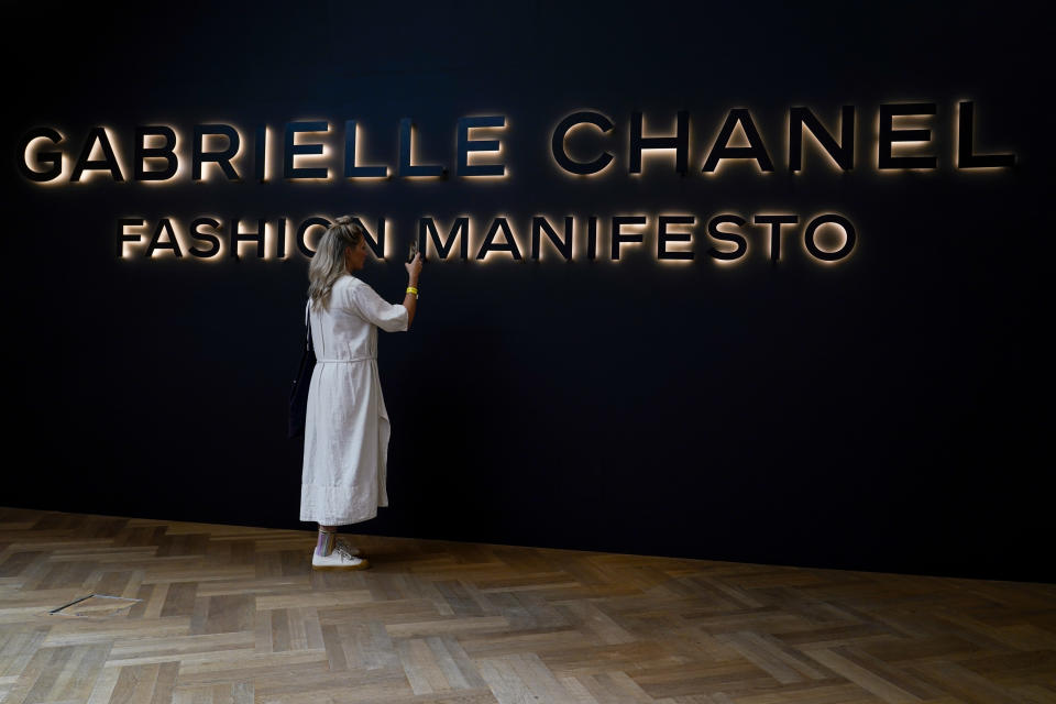 A visitor takes a phone picture at the entrance of the "Gabrielle Chanel. Fashion Manifesto" exhibition at the Victoria and Albert museum, in London, Tuesday, Sept. 12, 2023.(AP Photo/Alberto Pezzali)