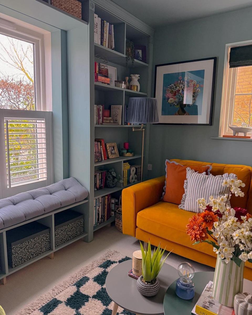 a room with a yellow couch and a bookcase