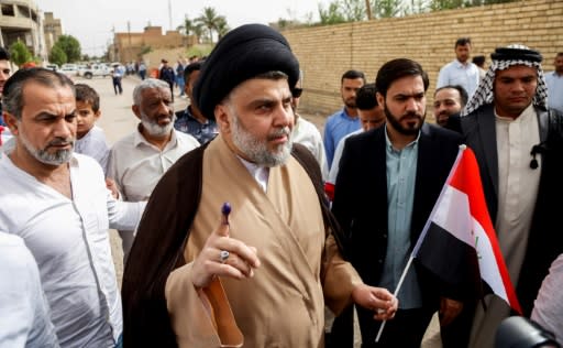 Iraqi Shiite cleric and leader Moqtada al-Sadr (C-L) shows his ink-stained finger outside a polling station in the central holy city of Najaf on May 12, 2018 as the country votes in parliamentary election