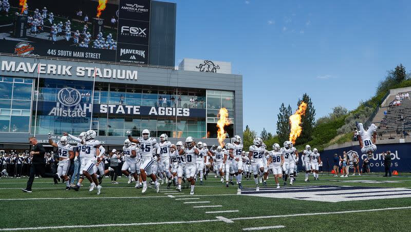 The Utah State Aggies storm the field before playing the UConn Huskies at the Maverik Stadium in Logan on Saturday, Aug. 27, 2022.