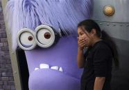 A girl laughs while standing with a purple Evil Minion character at the new "Despicable Me Minion Mayhem" ride during technical rehearsals for the new attraction at Universal Studios Hollywood in Universal City, California March 28, 2014. REUTERS/Jonathan Alcorn