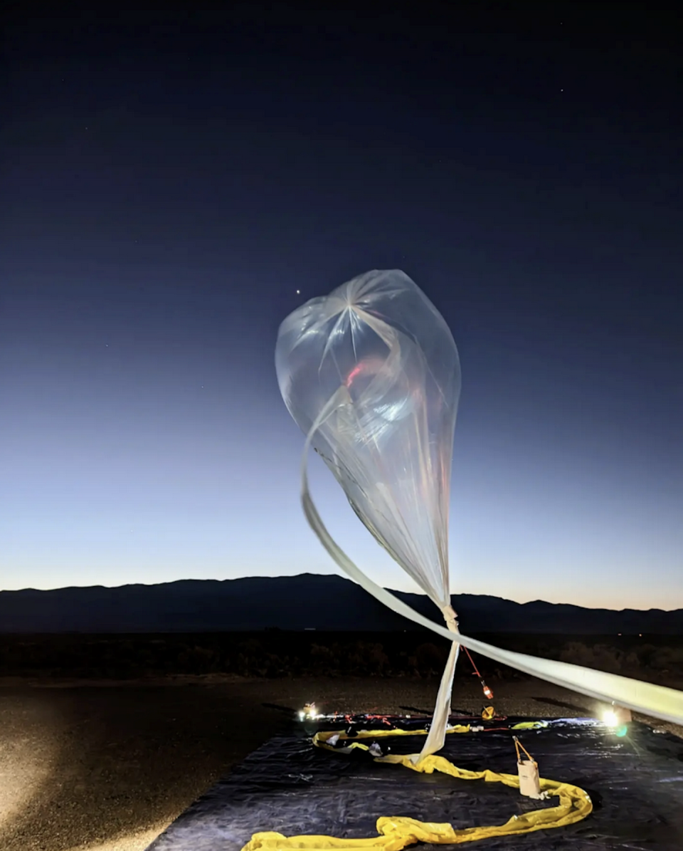 A large, translucent balloon rising into the sky and tethered to a ribbon.