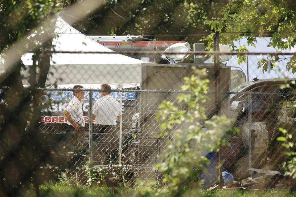 Law enforcement stand next to a home along Center Avenue in Lyons, Ill., where authorities believe they've uncovered bodies in the backyard on Saturday, Aug. 28, 2021. Authorities are planning to excavate the suburban Chicago backyard this weekend after two adult brothers found living in what police called a “hoarder home” said they had buried the bodies of their mother and sister there. (Stacey Wescott /Chicago Tribune via AP)