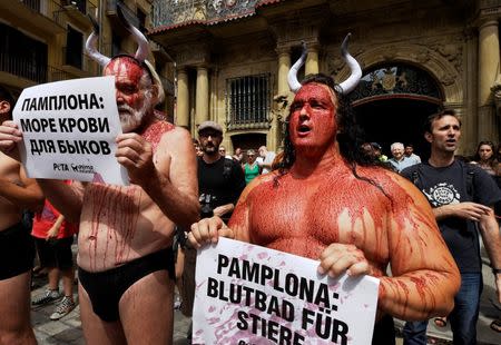 Animal rights protesters covered in fake blood demonstrate for the abolition of bull runs and bullfights a day before the start of the famous running of the bulls San Fermin festival in Pamplona, northern Spain, July 5, 2016. The banners read "Pamplona: sea of blood for bulls." REUTERS/Eloy Alonso