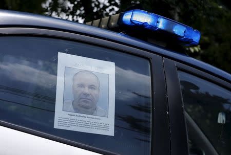 A police vehicle is seen a poster with a photo of drug lord Joaquin "El Chapo" Guzman offering a reward of 60 million Mexican pesos for information along a street in Mexico City July 16, 2015. REUTERS/Henry Romero