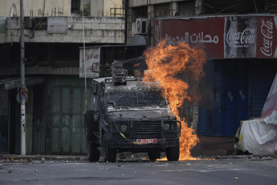 A Molotov cocktail thrown by a Palestinian protester explodes on an Israeli armored vehicle during clashes with Israeli security forces following a military raid in the West Bank city of Nablus, Friday, July 7, 2023. Palestinian health officials say two Palestinians were killed Friday by Israeli fire in the occupied West Bank, days after Israel concluded a two-day offensive meant to crack down on militants. (AP Photo/Majdi Mohammed)