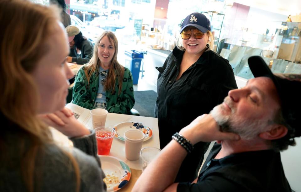 People interact around a coffee shop table.