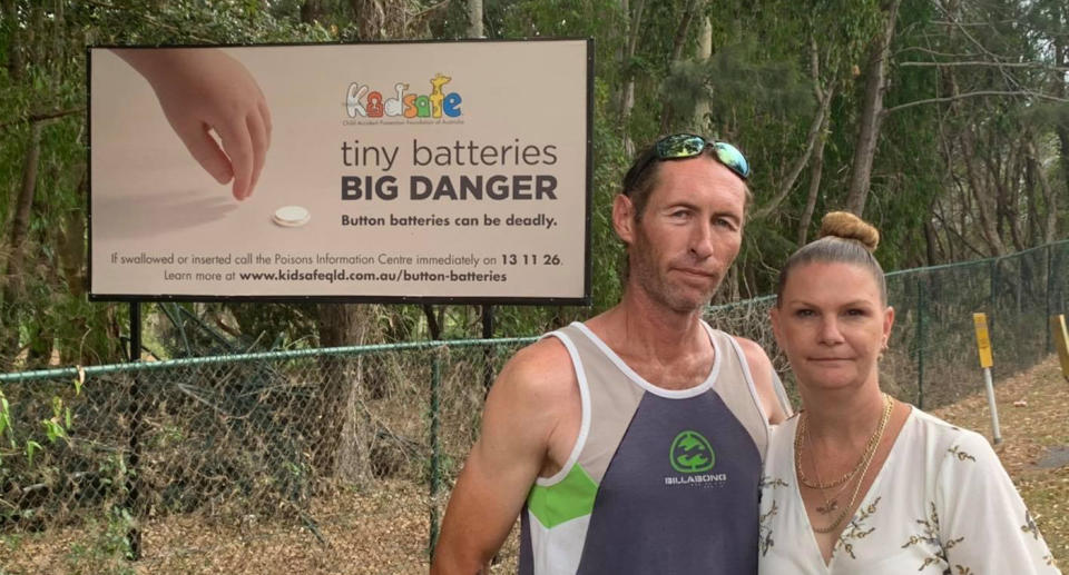 David (left) and Lorraine Conway (right) in front of a billboard warning about the dangers of button batteries.