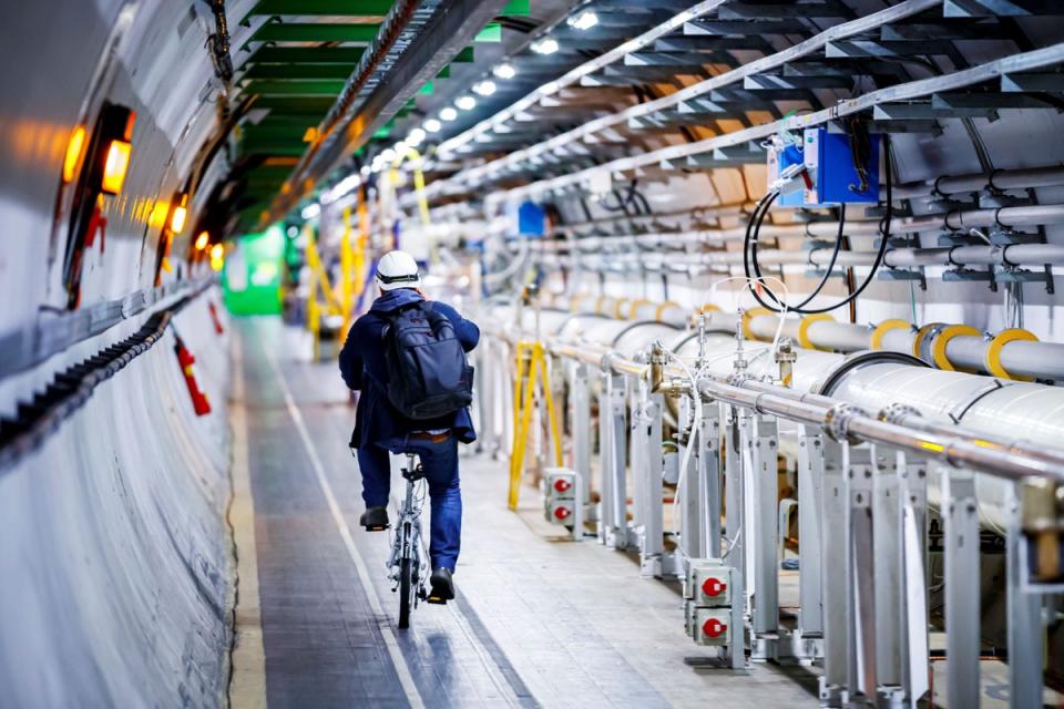 A man rides his bicycle along the underground Large Hadron Collider during its hiatus in 2020. The particle accelerator began smashing particles against on Tuesday 5 July (AFP via Getty Images)