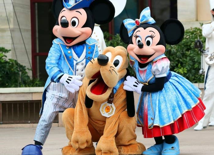 Costumed versions of Mickey, Minnie, and Pluto at a Disney park