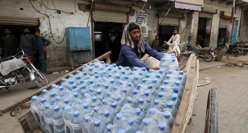 A man in Jacobabad unpacks water bottles.