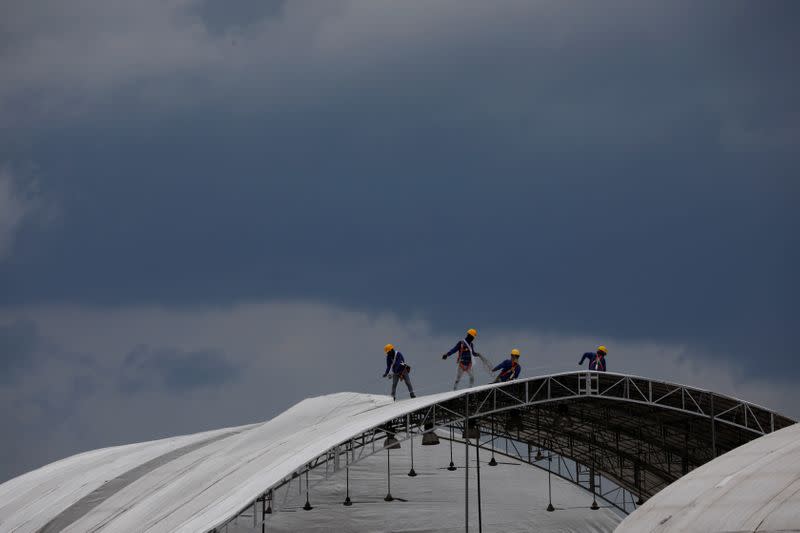 Workers construct outdoor building structures which will house an additional 1700 beds at Changi Exhibition Centre, in Singapore