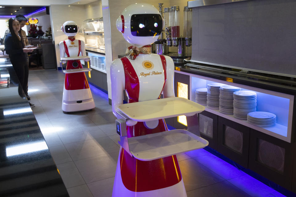 Leah Hu, left, and her brother Leon demonstrate the use of robots for serving purposes or for dirty dishes collection, as part of a tryout of measures to respect social distancing and help curb the spread of the COVID-19 coronavirus, at the family's Royal Palace restaurant in Renesse, south-western Netherlands, Wednesday, May 27, 2020. (AP Photo/Peter Dejong)