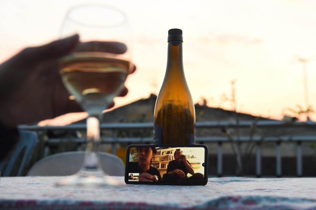 A woman drinks a glass of wine as she speaks and shares a drink with friends via a video call on March 26, 2020, in Bordeaux, southwestern France: NICOLAS TUCAT/AFP via Getty Images