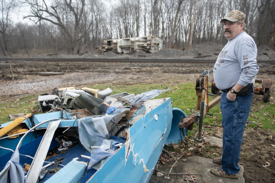 Chuck Knight, who witnessed a Nov. 1 train derailment in Ravenna Township, shows his boat that was destroyed by a train car as a derailed car sits nearby.