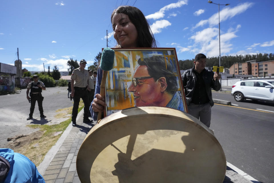 A supporter of slain presidential candidate Fernando Villavicencio holds his photo and a drum outside the cemetery during his funeral in Quito, Ecuador, Friday, Aug. 11, 2023. The 59-year-old was fatally shot at a political rally on Aug. 9 in Quito. (AP Photo/Dolores Ochoa)