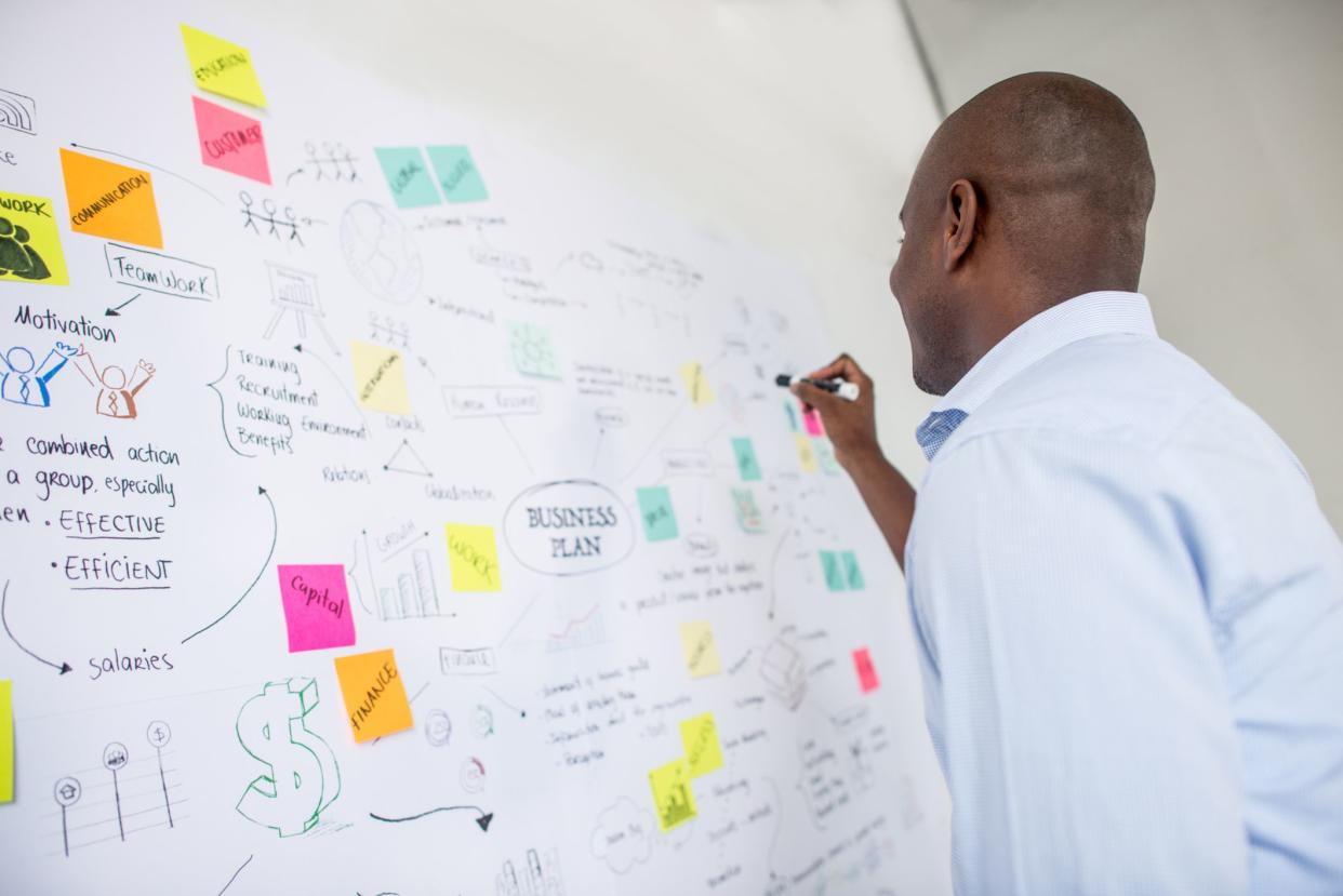 Successful African American business man drawing a plan on a wall chart