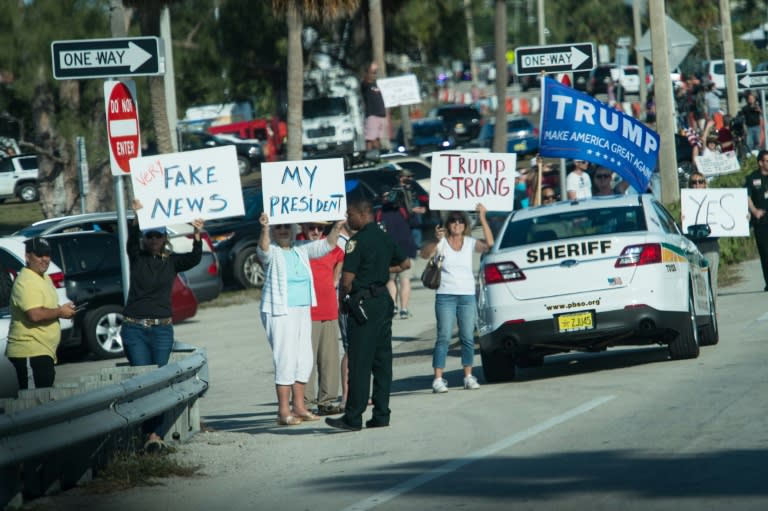 Supporters of US President Donald Trump hold signs as his motorcade drives by in Palm Beach, Florida, near his Mar-a-Lago resort