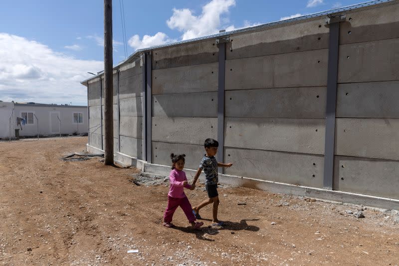 FILE PHOTO: Children walk next to a newly built concrete wall inside the Ritsona camp for refugees and migrants