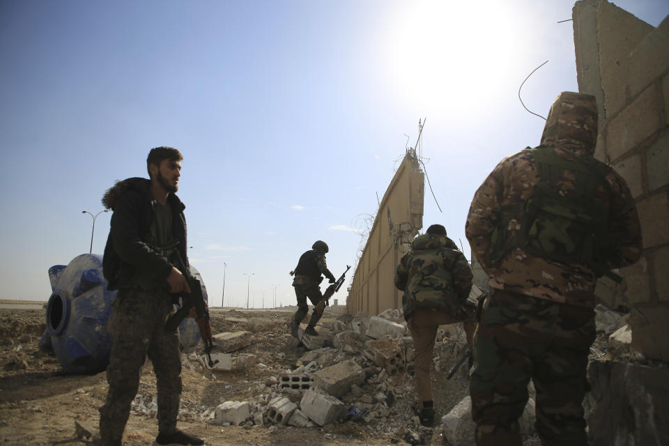 Kurdish-led Syrian Democratic Forces fighters take their positions at the defense wall of Gweiran Prison in Hassakeh, northeast Syria, Sunday, Jan. 23, 2022. Clashes between U.S.-backed Syrian Kurdish fighters and militants continued for a fourth day Sunday near a prison in northeastern Syria that houses thousands of members of the Islamic State group, the Kurdish force said. (AP Photo/Hogir Al Abdo)