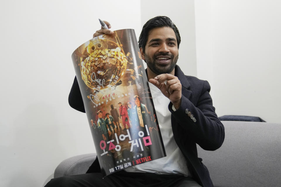 Indian actor Anupam Tripathi, who starred in the Netflix series "Squid Game", holds a "Squid Game" poster during an interview in Seoul, South Korea on Nov. 18, 2021. Tripathi was named one of AP's breakthrough entertainers of the year. (AP Photo/Ahn Young-joon).
