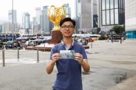 Kalok Leung, who was born four months after the Hong Kong's handover to Chinese rule in 1997, poses with his childhood photo which was taken at the same spot in 2002, at Golden Bauhinia Square in Hong Kong, China June 15, 2017. REUTERS/Tyrone Siu