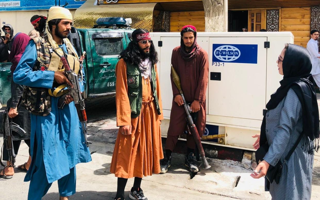 An unidentified woman is seen talking to Taliban fighters in the street in Kabul - EPN/Newscom / Avalon