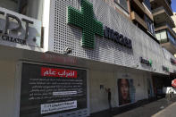 A boy knocks on a door of a closed pharmacy in Beirut, Lebanon, Friday, June 11, 2021. Pharmacies across Lebanon began a two-day strike Friday, protesting severe shortages in medicinal supplies that is increasingly putting them in confrontation with customers and patients searching for medicines. The shortages are affecting everything from medicines for chronic illnesses to pain relievers to infant milk. (AP Photo/Bilal Hussein)