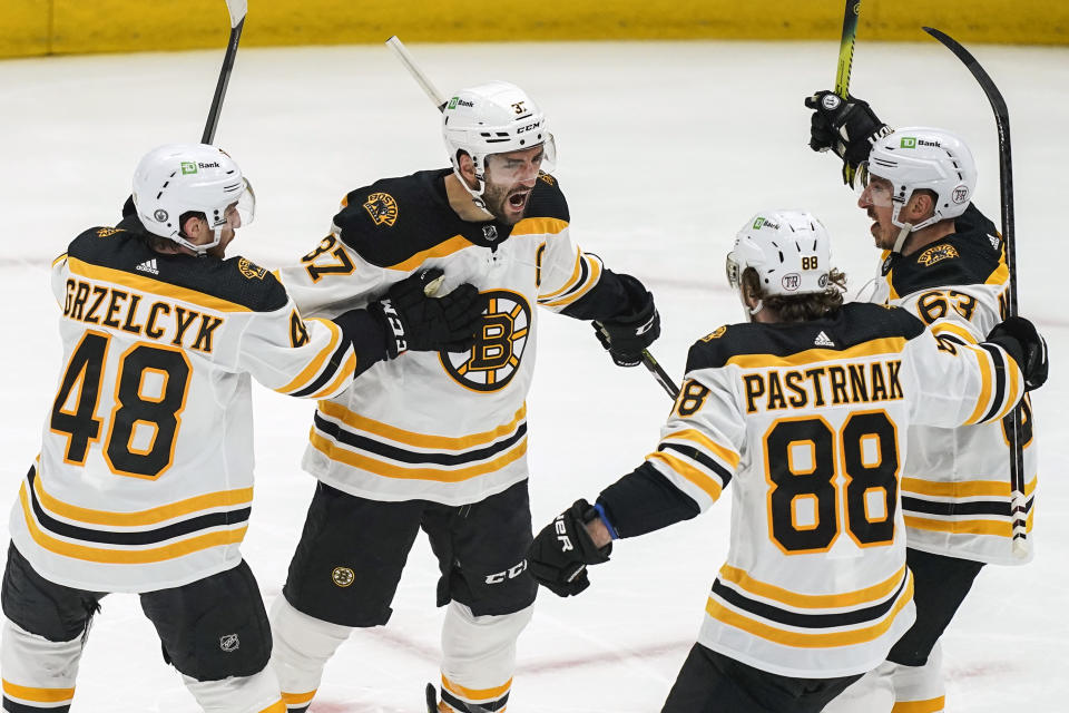 Boston Bruins center Patrice Bergeron (37) celebrates his goal with defenseman Matt Grzelcyk (48), right wing David Pastrnak (88) and center Brad Marchand (63) during the first period of Game 2 of an NHL hockey Stanley Cup first-round playoff series against the Washington Capitals Monday, May 17, 2021, in Washington. (AP Photo/Alex Brandon)