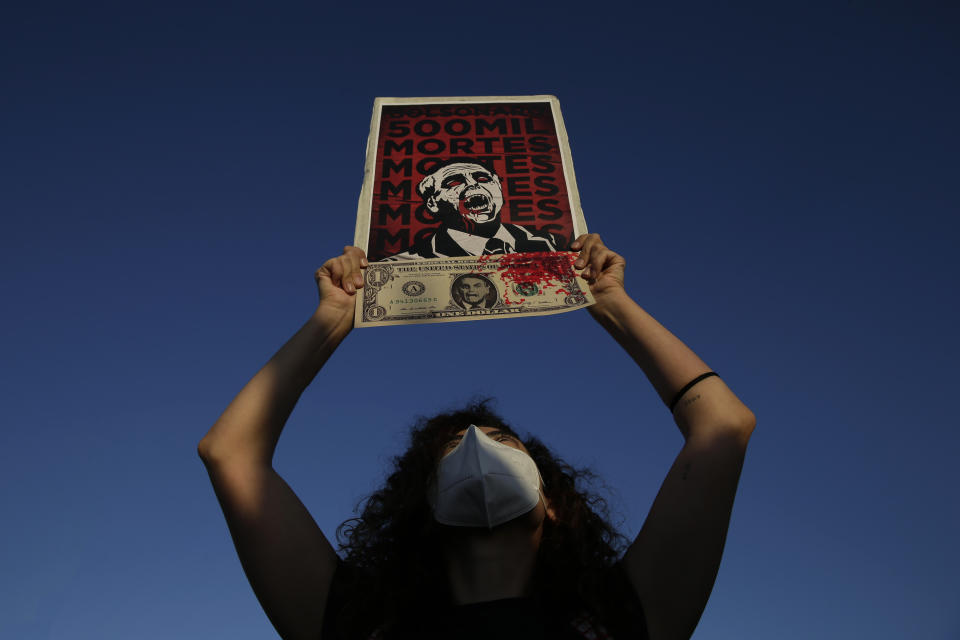 FILE - In this Wednesday, June 30, 2021 file photo, a demonstrator holds a poster with an image of President Jair Bolsonaro and a message that reads in Portuguese: "500 thousand deaths", in reference to the deaths caused by COVID-19, during a protest outside Congress to demand that Bolsonaro resign, in Brasilia, Brazil. The coronavirus pandemic has upended life around the globe, but it has hasn’t stopped the spread of authoritarianism and extremism. Some researchers believe it may even have accelerated it, but curbing individual freedoms and boosting the reach of the state. Since COVID-19 hit, Hungary has banned children from being told about homosexuality. China shut Hong Kong’s last pro-democracy newspaper. Brazil’s president has extolled dictatorship. Belarus has hijacked a passenger plane. A Cambodian human rights lawyer calls the pandemic “a dictator's dream opportunity.” But there are also resistance movements, as protesters from Hungary to Brazil take to the streets to defend democracy. (AP Photo/Eraldo Peres, FIle)