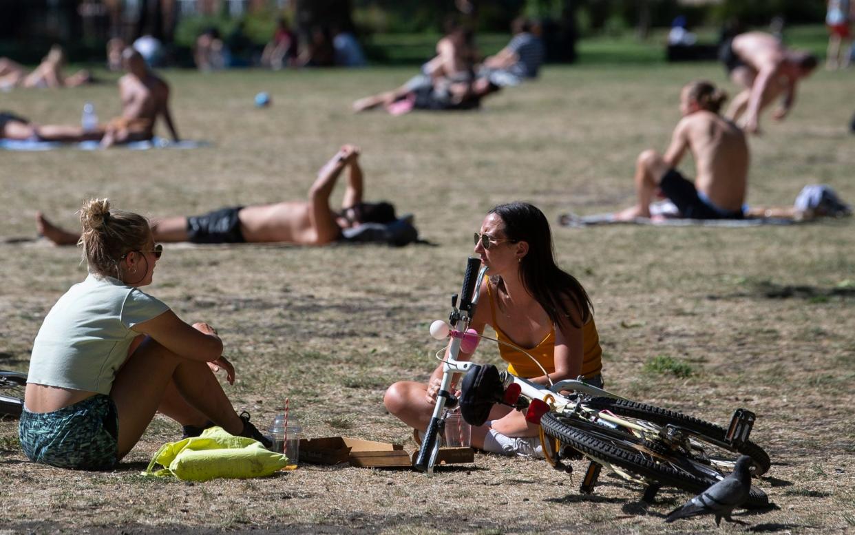 People enjoy the sun in London Fields park in East London - PA