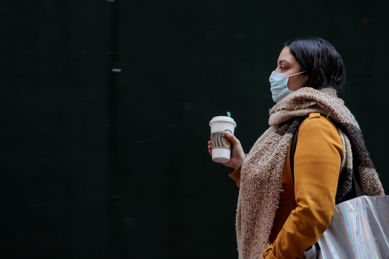 FILE PHOTO: A woman wears a mask on Wall St. near the NYSE in New York