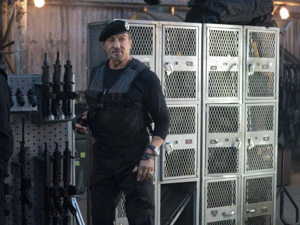 Sylvester Stallone by a rack of guns