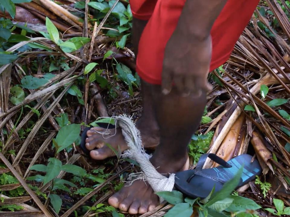 A man's bare feet stand inside a piece of rope called a peconha.